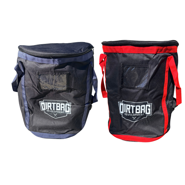 Two soft-sided DIRTBAG Development equipment bags shown side by side on a white background. The left bag is navy blue with dark blue accents, and the right bag is black with red accents.